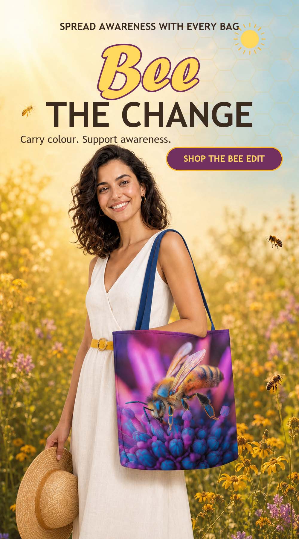 Smiling woman in an ivory summer dress carrying a vivid purple bee print tote in a sunlit wildflower meadow beneath Bee the Change.